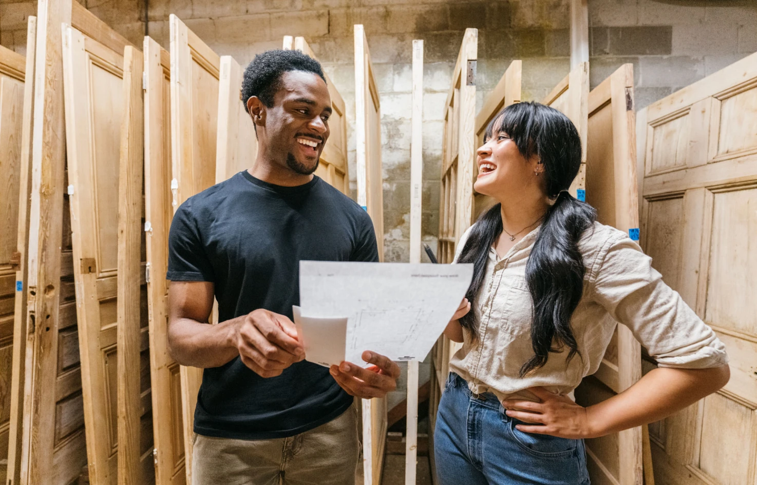 Two people discussing plans in wood workshop.